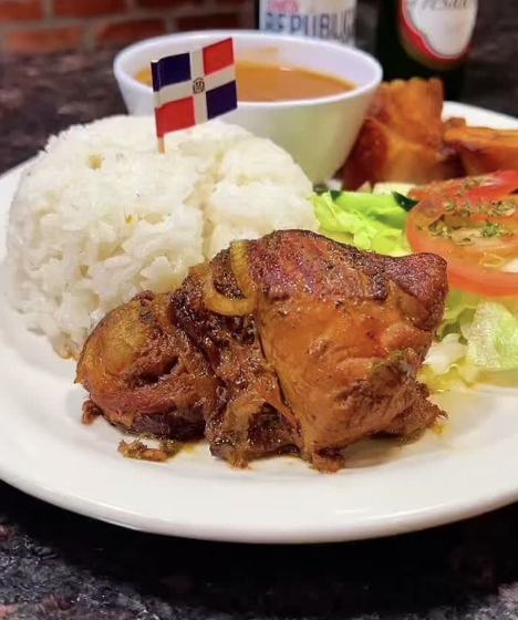 Pollo guisado with white rice and a Dominican flag